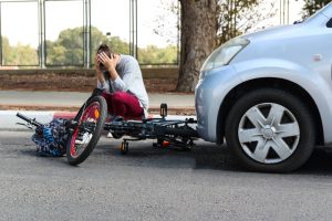a woman holding her head near a traffic accident between electric e bike and car