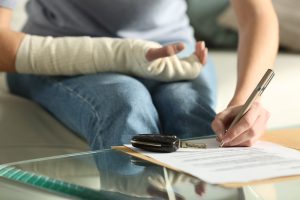 lady hands with broken arm signing insurance document after car accident at home